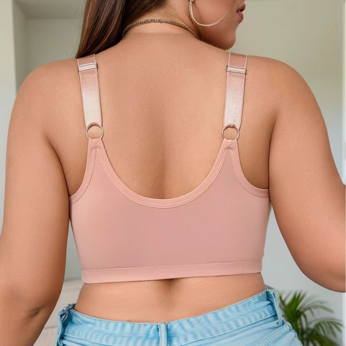 Person wearing a pink sports bra and blue jeans with a neutral background