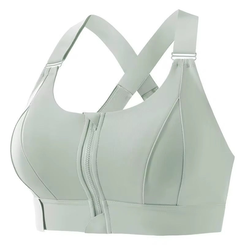 A sage green seamless sports bra with a front zipper and adjustable criss-cross back straps, shown against a plain white background.