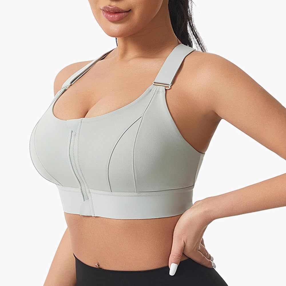A woman wearing a light gray athletic sports bra with a front zipper and adjustable shoulder straps, shown against a plain light background.