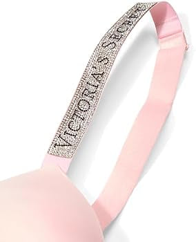 A close-up of a light pink bra strap featuring a rhinestone-embellished band with the text 'VICTORIA'S SECRET' in black lettering.