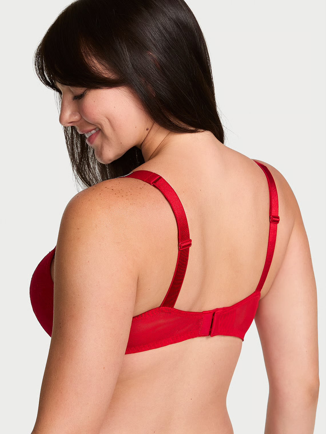 A woman shown from the back wearing a bright red underwire bra against a light gray studio background.