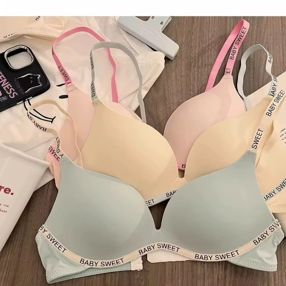 Two bras with 'Baby Sweet' trim on a wooden surface