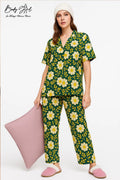 Woman wearing a green floral pajama set with a white pillow on a white background